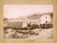 Reproducción de una vista general de personal ferroviario de la Compañía de los Caminos de Hierro del Norte de España posando en la estación de Tarrasa, junto con la locomotora de vapor 1401 de la compañía (CA. 1899-1900)