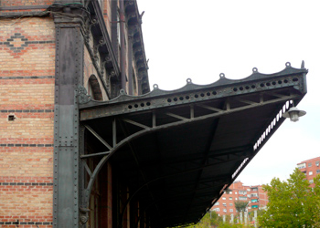 Marquesina de hierro del antiguo vestbulo en el pabelln de salidas del edificio de viajeros. Muros de fbrica de ladrillo con franjas de dos tonalidades de rojo y decoracin pintada en negro.